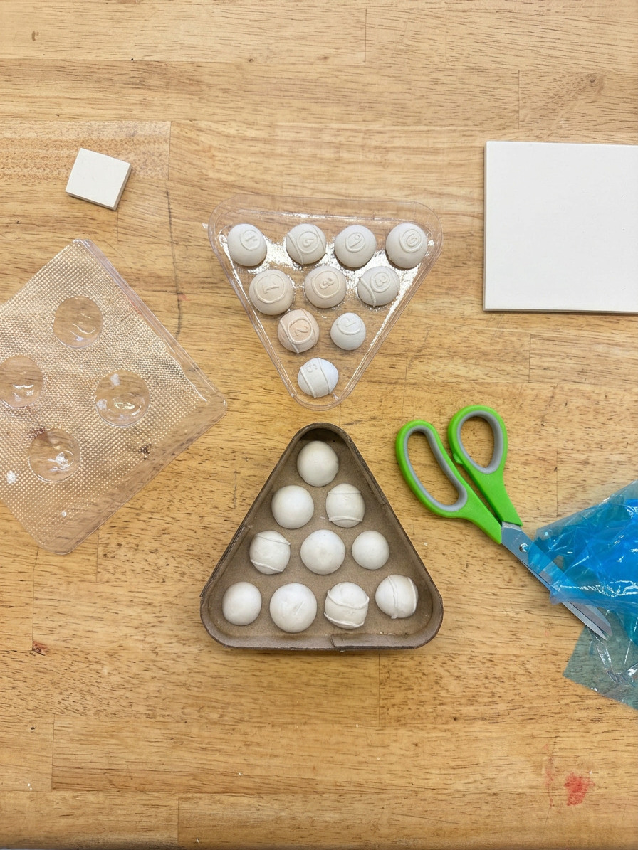 Workbench showing clay balls, molds and scissors mid-process.