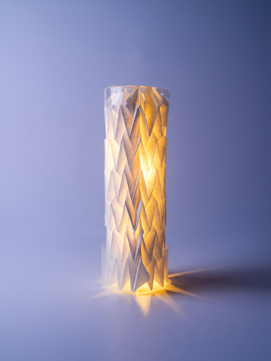 Folded paper lantern lit from within, glowing warm against a soft wall.